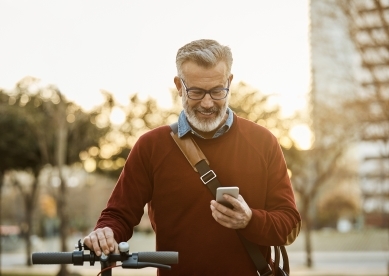 Man looking at phone while walking with bike